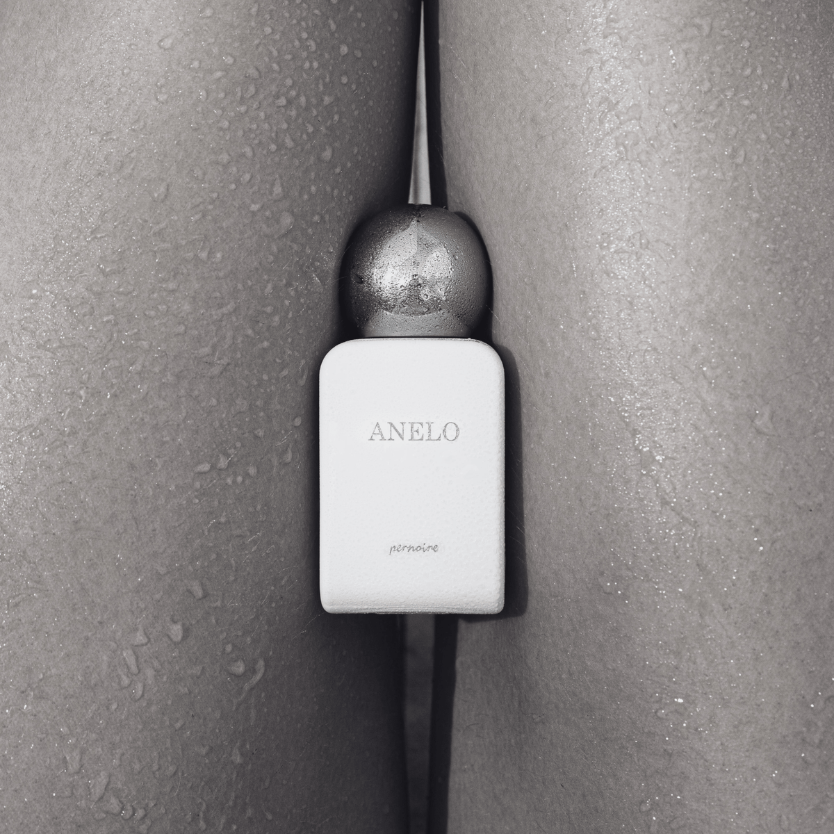 White ANELO bottle between bare thighs with water droplets on the skin.
