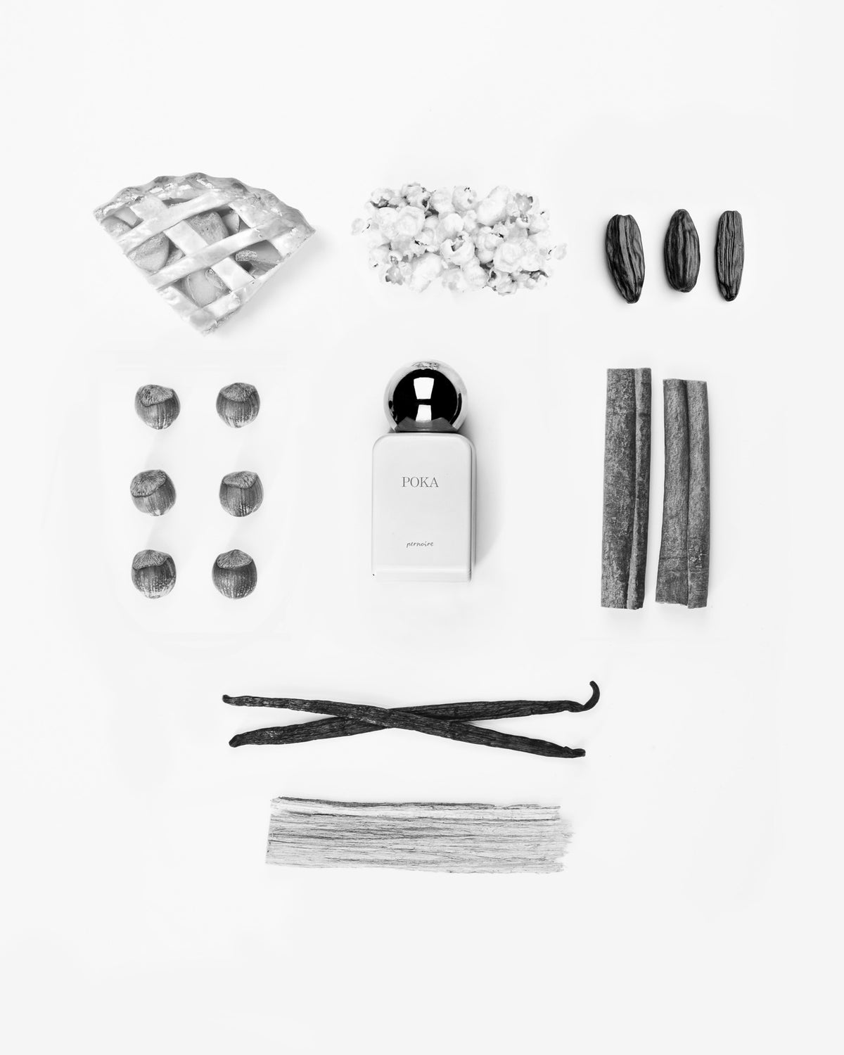 White POKA bottle with apple pie, popcorn, hazelnuts, cinnamon, tonka beans, vanilla and wood on white.