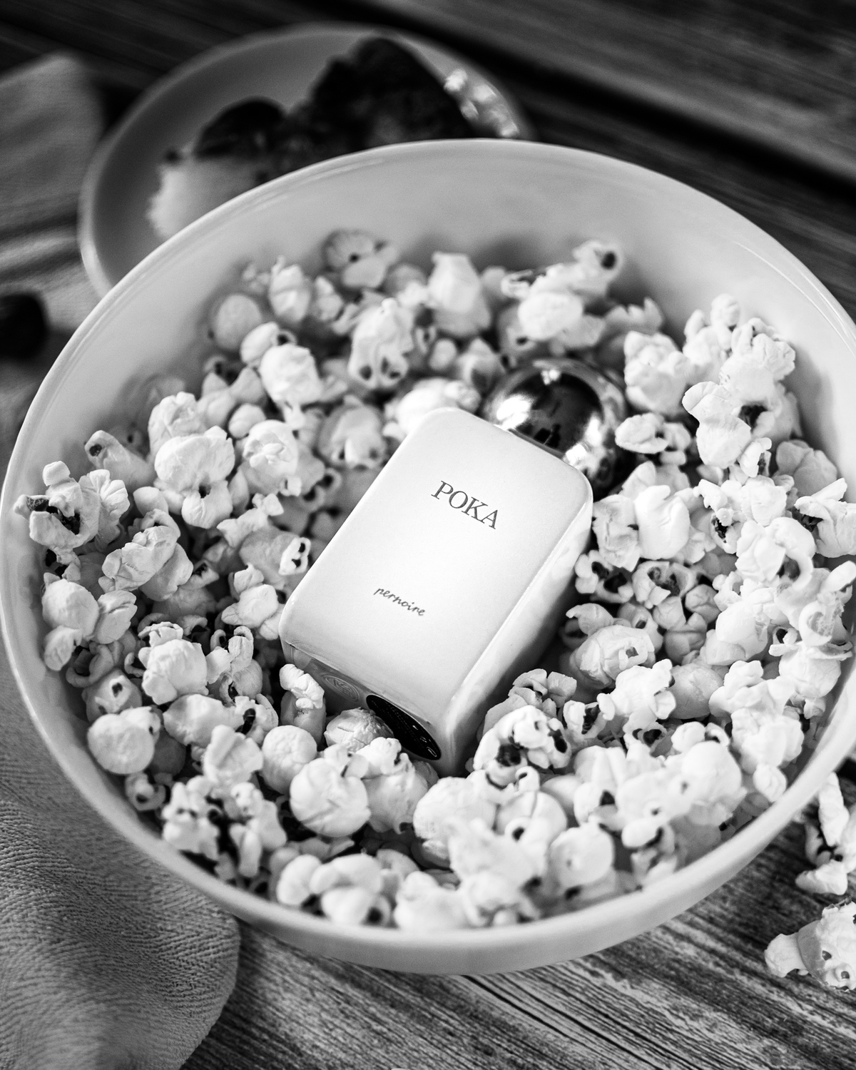 White POKA bottle lying in a bowl filled with popcorn.