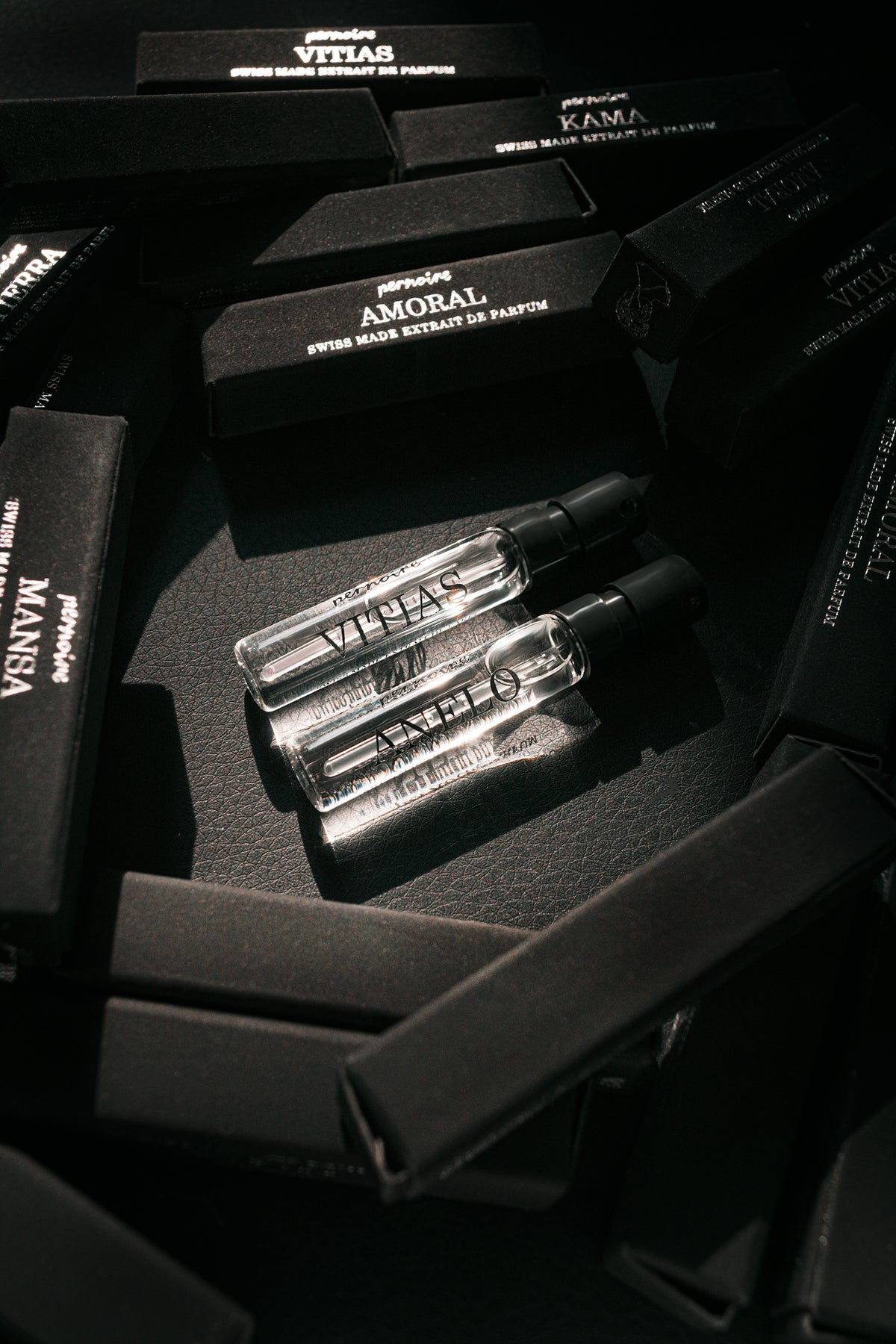Anelo and Vitias perfume sample sprays on black pernoire sample packaging.